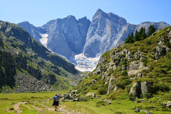Hiker on a trek in the national park Pyrenees. Mountain Vignemale in the background. Occitanie in south of France.