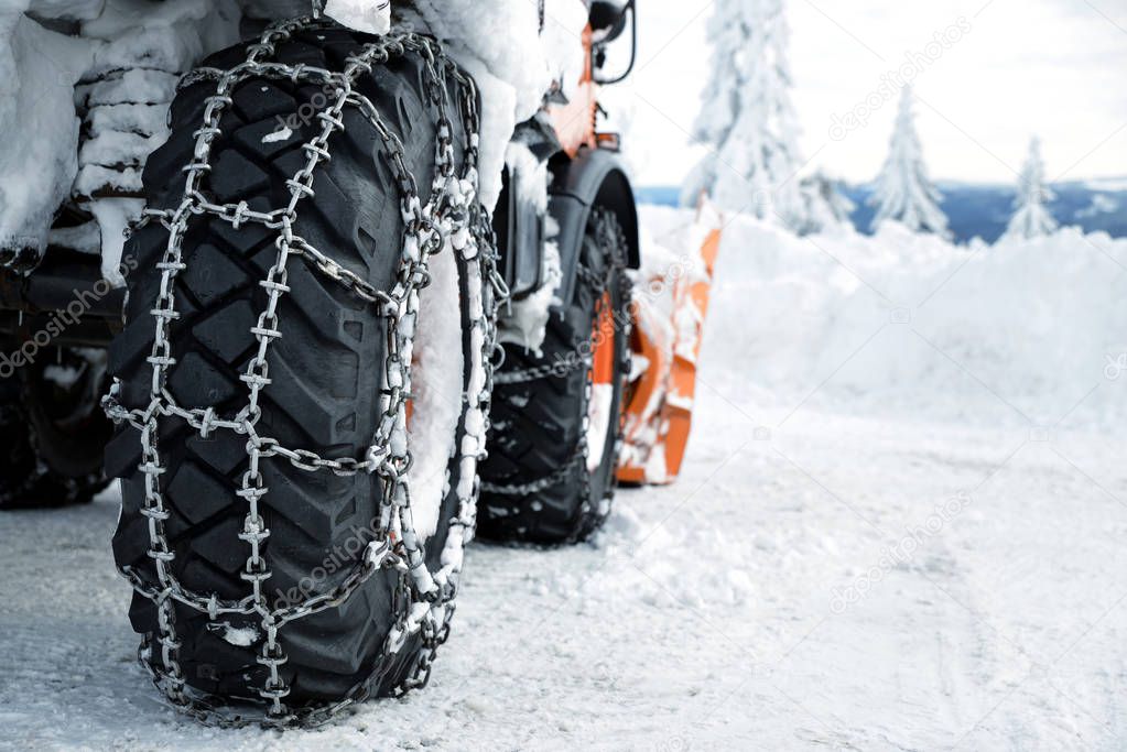 Car wheels equipped with snow chains. Winter season.