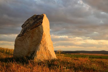 Günbatımı çayır üzerinde antik taş menhir.