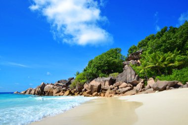 Seyşeller 'deki La Digue Adası' nda büyük granit taşlı Petite Anse plajı. Güneşli gökyüzü olan tropik bir yer..