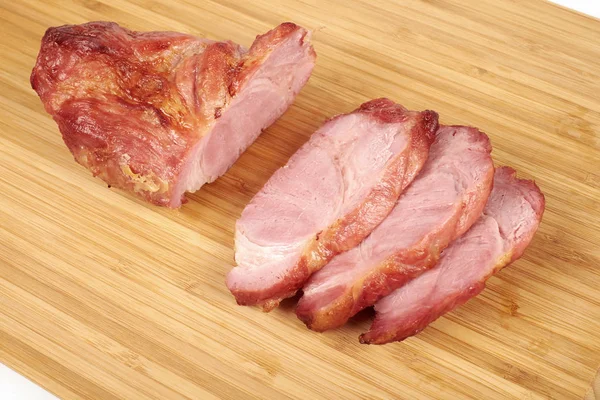 Carne asada de cerdo cocida en rodajas sobre tabla de cortar de madera sobre fondo blanco — Foto de Stock