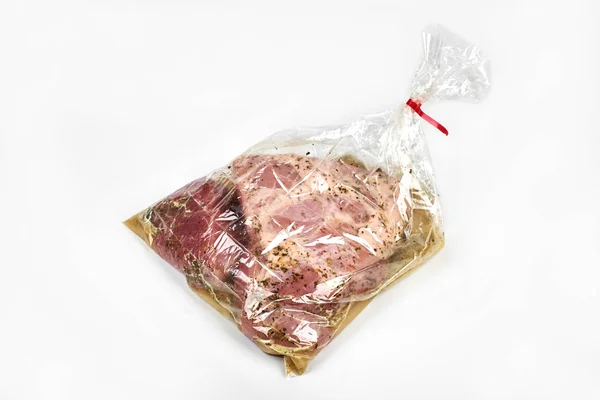 Carne fresca envasada en una manga con especias, para hornear está lista para hornear, aislada sobre fondo blanco — Foto de Stock
