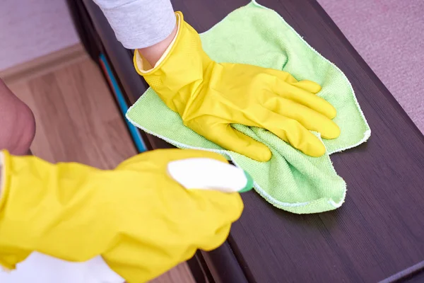 A picture of hands in yellow gloves cleaning the wooden surface