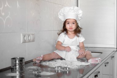 Güzel küçük kız mutfakta yemek yapmayı öğreniyor.