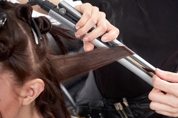 Closeup hairdresser makes hairstyle for young woman in beauty salon — Stock Photo, Image