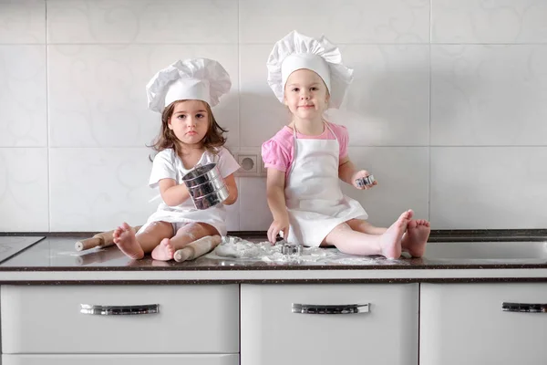 Две маленькие девочки готовят еду на кухне дома — стоковое фото