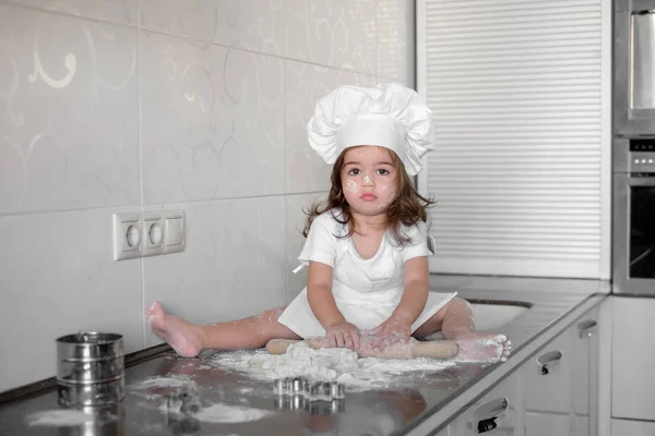 Маленькая девочка делает тесто и печенье на кухне — стоковое фото