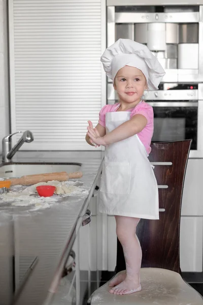 Linda menina aprende a cozinhar uma refeição na cozinha — Fotografia de Stock