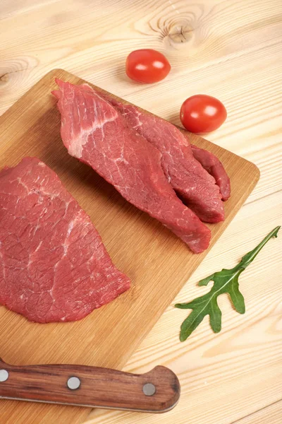 Carne cruda en rodajas en tabla de cortar y verduras —  Fotos de Stock