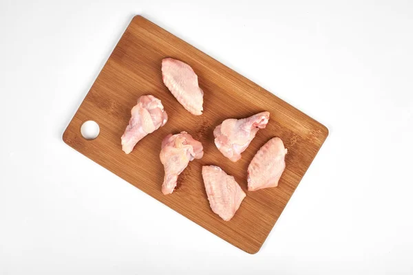 cut raw chicken wings on a cutting board isolated on white background.