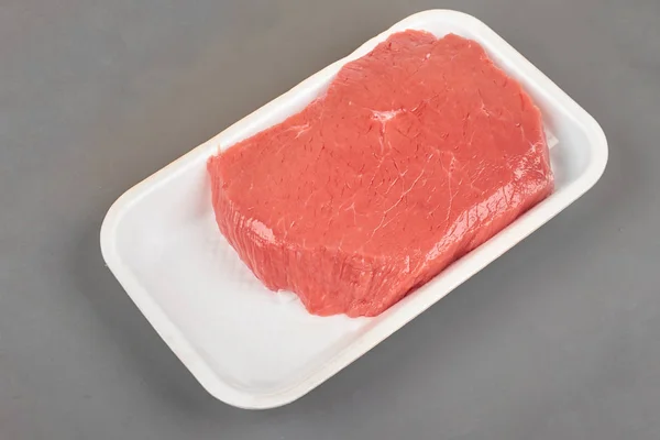 Fresh raw meat in a white tray on grey background. — Stock Photo, Image