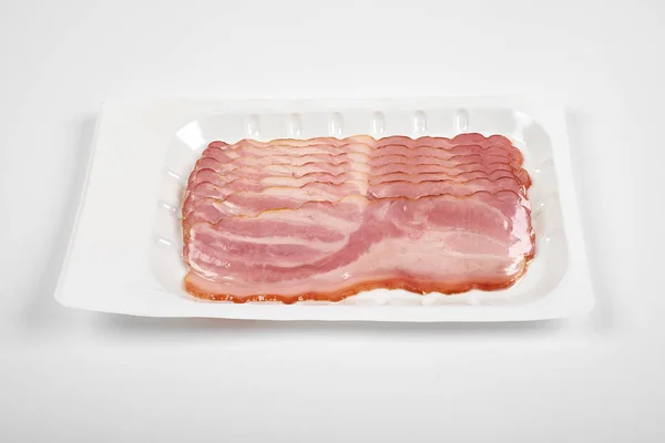 Fatias de bacon no pacote, isoladas em fundo branco — Fotografia de Stock