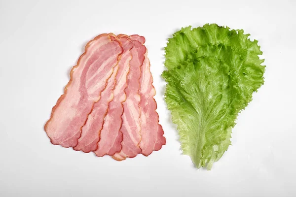 Schweinespeck und Salat in Scheiben auf weißem Hintergrund — Stockfoto