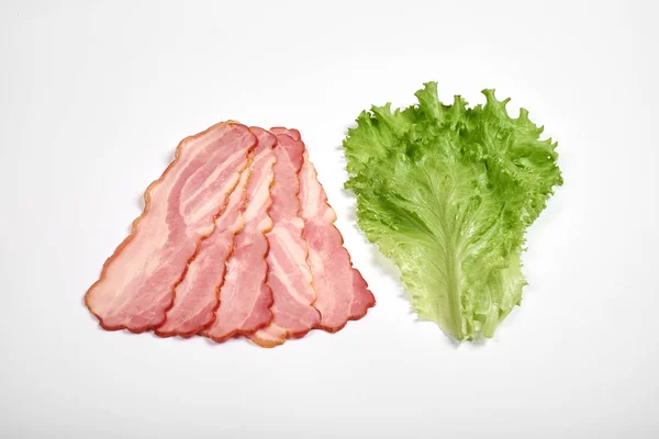 Schweinespeck und Salat in Scheiben auf weißem Hintergrund — Stockfoto