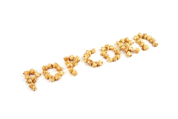 The word POPKORN is laid out from pieces of caramel popcorn on a white background. — Stock Photo, Image