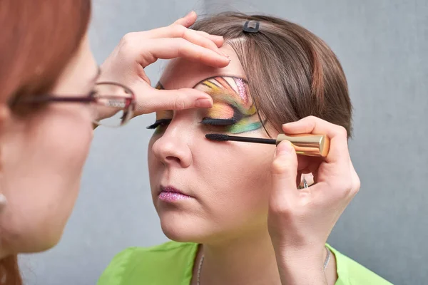 Tvoří umělec dělá profesionální make-up mladé ženy. — Stock fotografie