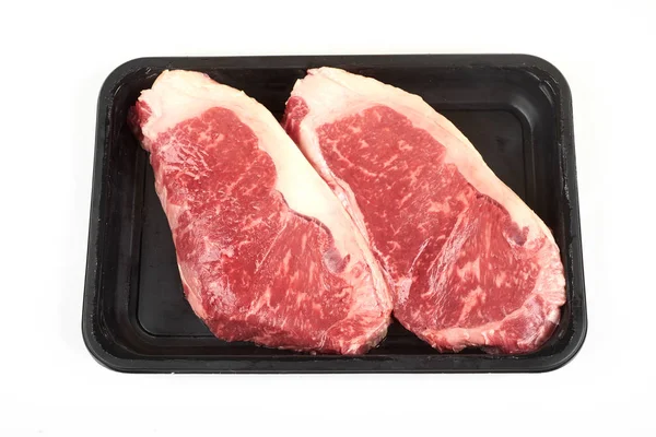 Raw sirloin beef steak in plastic packaging tray. — Stock Photo, Image