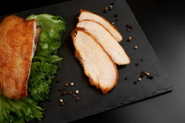 Kızarmış, dilimlenmiş tavuk göğsü siyah bir tabakta..