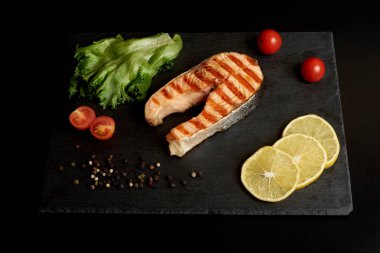 Izgara alabalık biftek bir domates ve kayrak bir tabak salata.