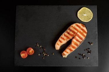 Bir biber, limon ve kopya alanı ile kayrak bir tabakta domates ızgara somon biftek