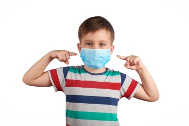 Tıbbi maske takan ve maskeyi gösteren genç bir çocuk. Tıbbi maske takmak iyidir. corona virüsü konsepti.
