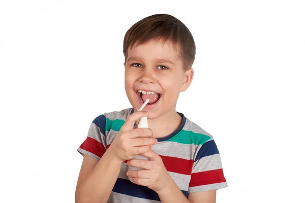 Den leende pojken sprejar sig i munnen med en spray från smärtan i hennes hals. Isolerad på en vit bakgrund. — Stockfoto