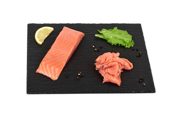Potongan daging salmon di papan serpih hitam, dengan lemon dan salad. Pada latar belakang putih — Stok Foto