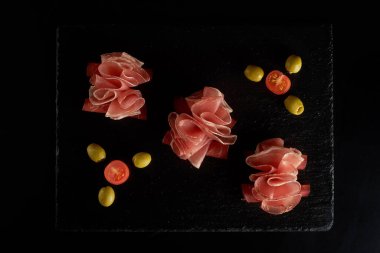 Güzel servis edilmiş prosciutto ya da jamon siyah tahtada..