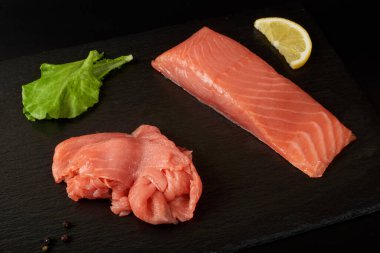 Siyah şist tahtasında dilimlenmiş kırmızı balık filetosu..