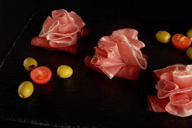 Mükemmel servis edilen prosciutto ya da jamon ve siyah tahtada zeytin..