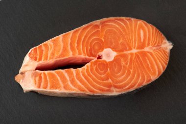 Somon bifteği çiğ balık pişirmeye hazır. Siyah tahta üzerinde üst görünüm.