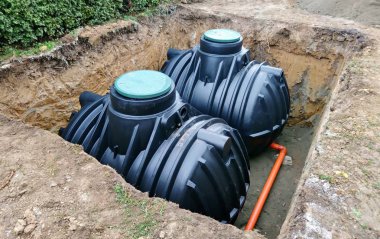 Two plastic underground storage tanks placed below ground for harvesting rainwater. The underground water septic tanks, for use as ecological recycling rainwater. Tank for home water harvest. clipart