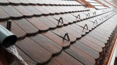 Şiddetli bir yağmur fırtınası sırasında damlalar kırmızı kiremitlerle damlıyor, yavaş çekim klibi.