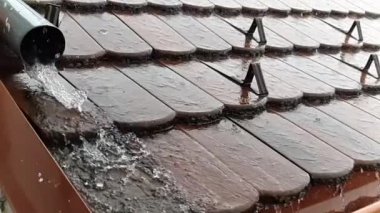 Şiddetli bir yağmur fırtınası sırasında damlalar kırmızı kiremitlerle damlıyor, yavaş çekim klibi.