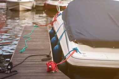 Mavi tuval yağmur paravan bir yıpranmış ahşap rıhtım ve arka planda bulanık bağlantı noktası ile kaplı modern Motorlu tekne ön cam ve yay güverte