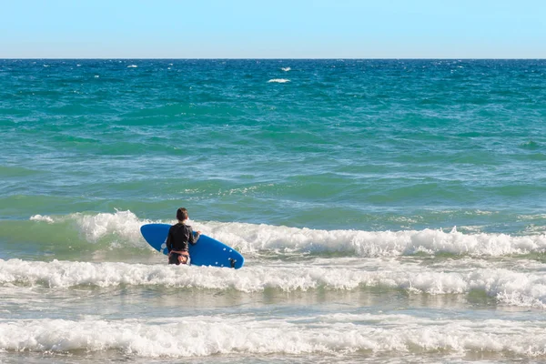 boy with surfboard standing in the water