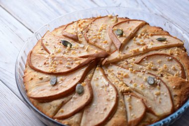 Ahşap zemin üzerinde cam bir kabın içindeki armutlu muhteşem turta.