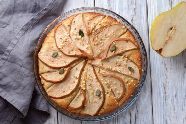 Ahşap zemin üzerinde cam bir kabın içindeki armutlu muhteşem turta.