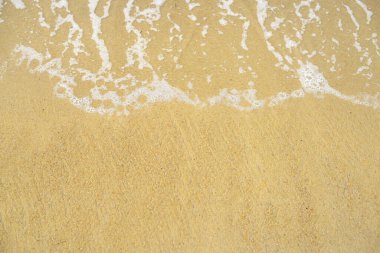 Kumlu sahilde yumuşak bir mavi okyanus dalgası. Arkaplan