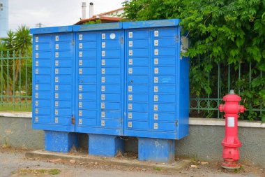 Caddedeki mavi posta kutuları ve kırmızı yangın musluğu.