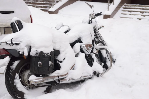 Winter in Russia. Abandoned motorcycle covered with a thick layer of snow