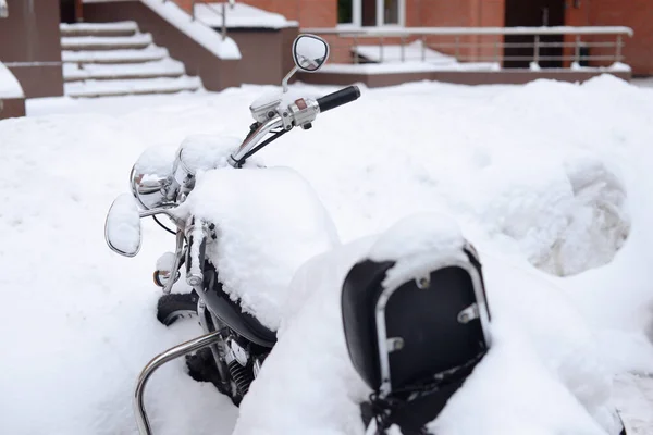 Winter in Russia. Abandoned motorcycle covered with a thick layer of snow