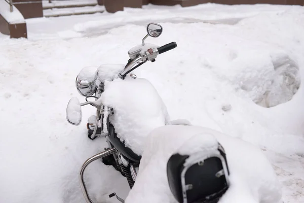 Winter in Russia. Abandoned motorcycle covered with a thick layer of snow