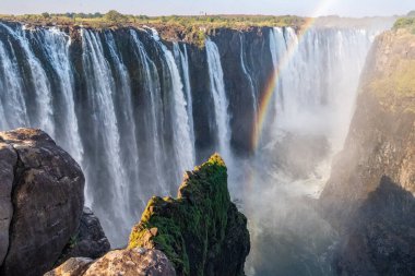 Closeup of the Victoria falls, on the Zimbabwe-Zambia Border. A small rainbow emerges in front of the falls.