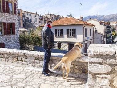 Vence, Fransa, üzerinde 8 Mart 2018. Kadın ve köpek bir anket sitesi pitoresk evleri şehir Mahallesi'nde bir dağ yamacında bakmak