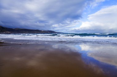 Atlantik Okyanusu kıyısında sörf dalgaları. Gökyüzünün suya yansıyan
