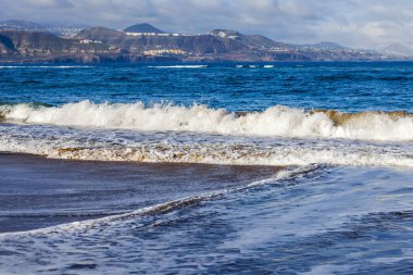 Bir sörf, bulutlu havalarda Atlantik Okyanusu kıyısında pitoresk dalgalar