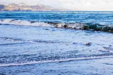 Bir sörf, bulutlu havalarda Atlantik Okyanusu kıyısında pitoresk dalgalar