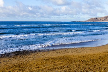 Bir sörf, bulutlu havalarda Atlantik Okyanusu kıyısında pitoresk dalgalar