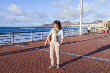 Las Palmas de Gran Canaria, İspanya, 10 Ocak 2018 üzerinde. Kış güneşi Playa de Las Canteras beach Atlantik Okyanusu kıyısında ışıklar. Çekici kadın dolgu üzerinde yürüyor